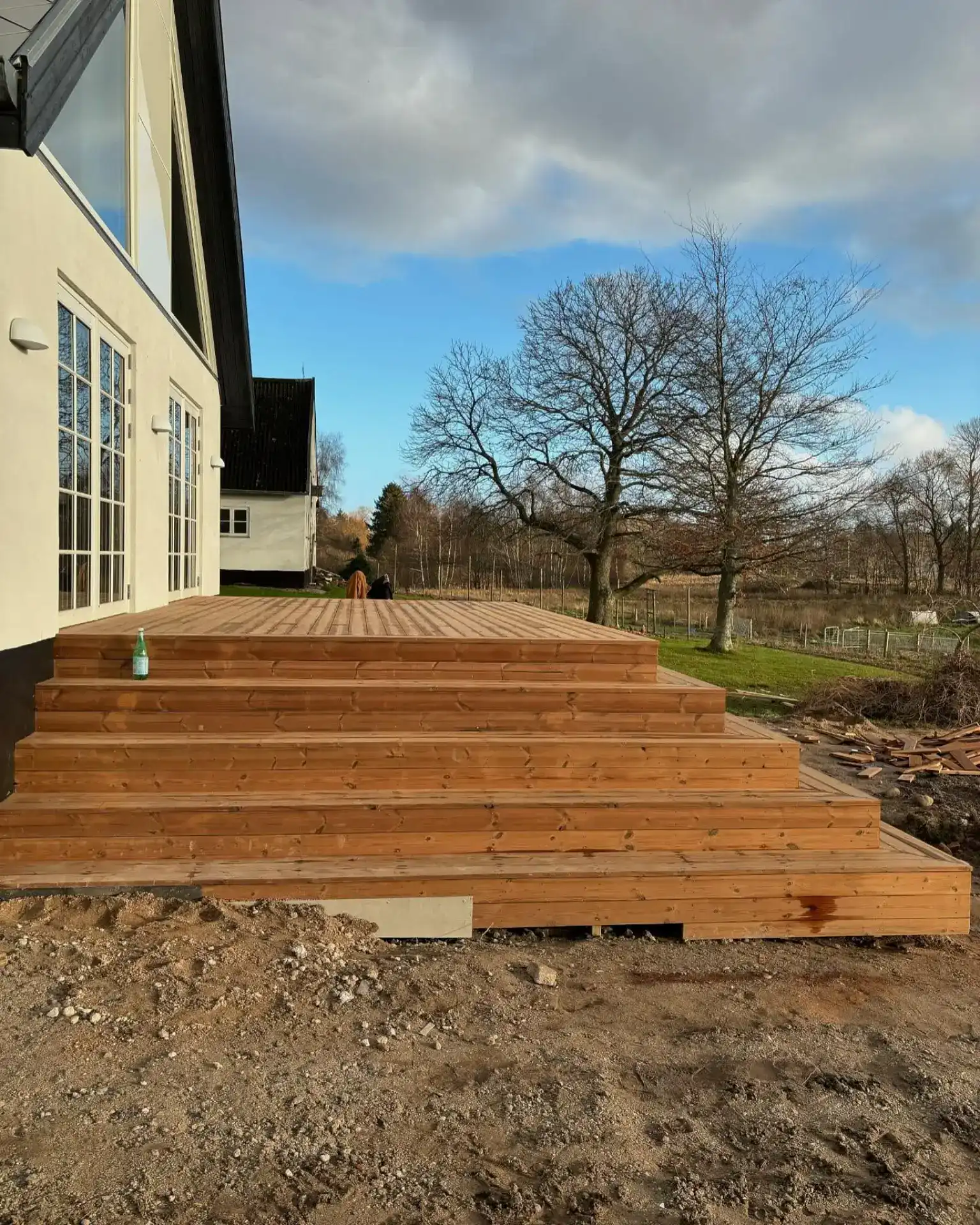 Træterrasse under opførelse ved hus i naturen, klar til brug.