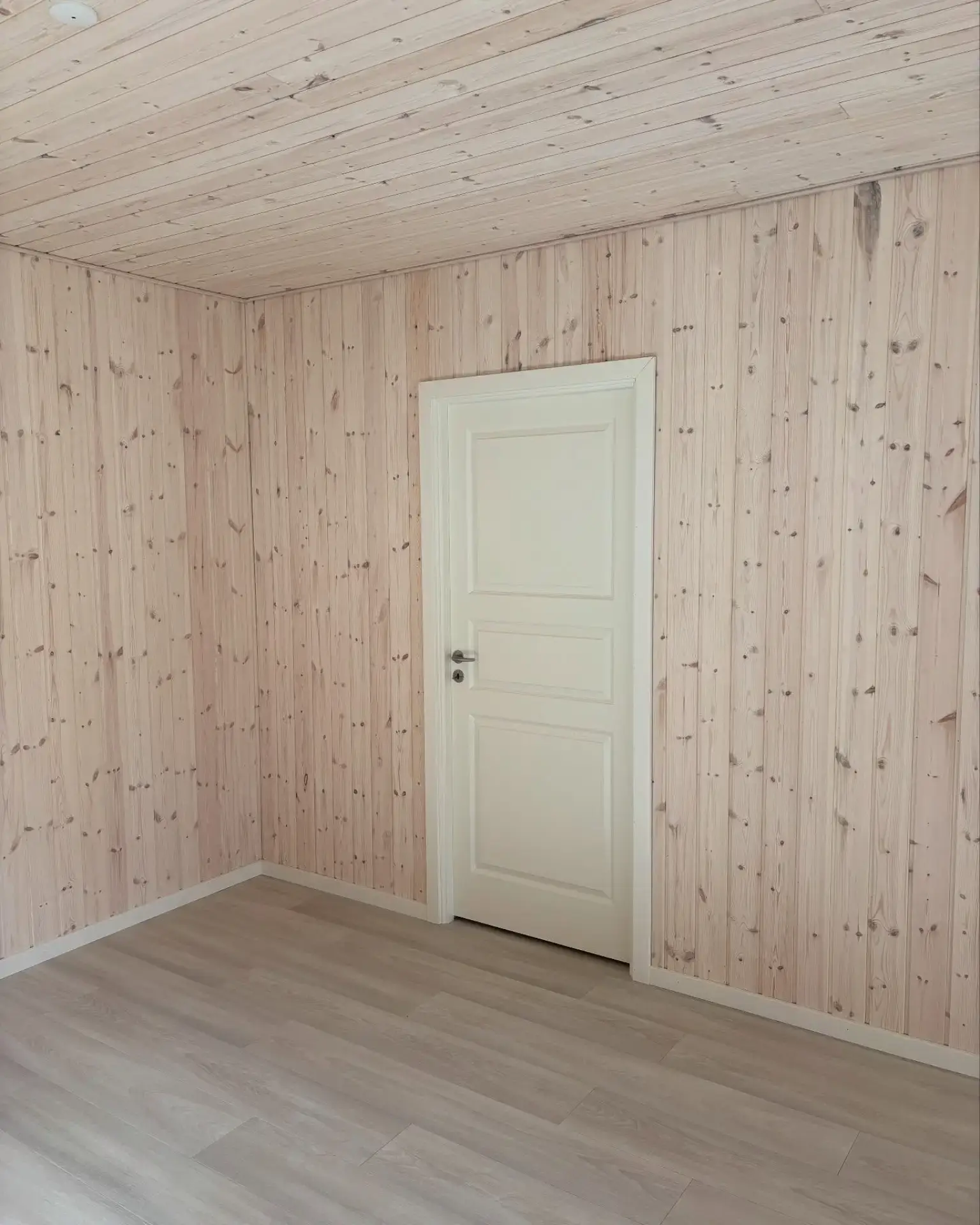 Billedet viser et rum med træbeklædning på vægge og loft, udført af Tømrermester Leit.