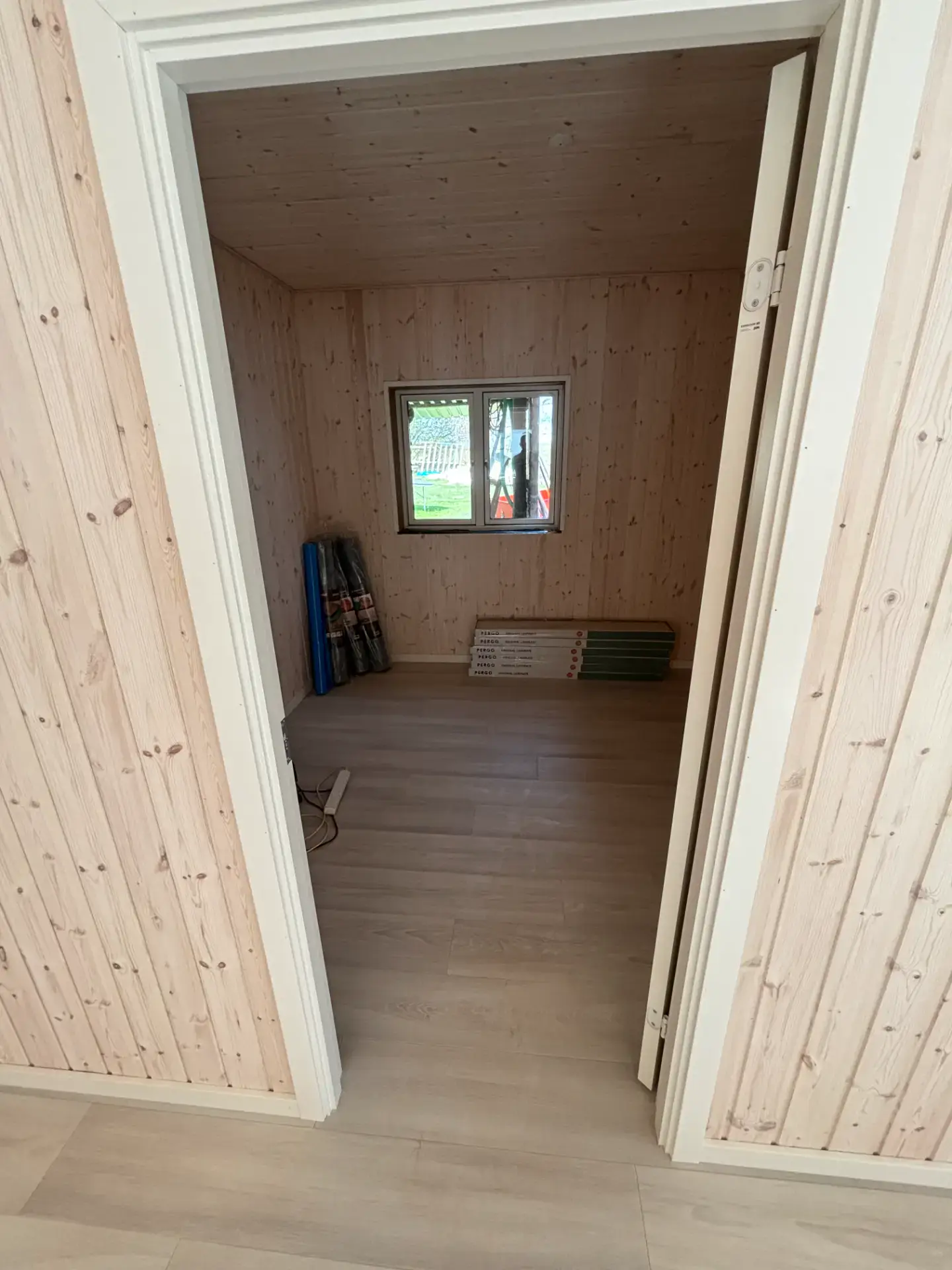 Lille værelse med trævægge og gulv, klar til indretning.
