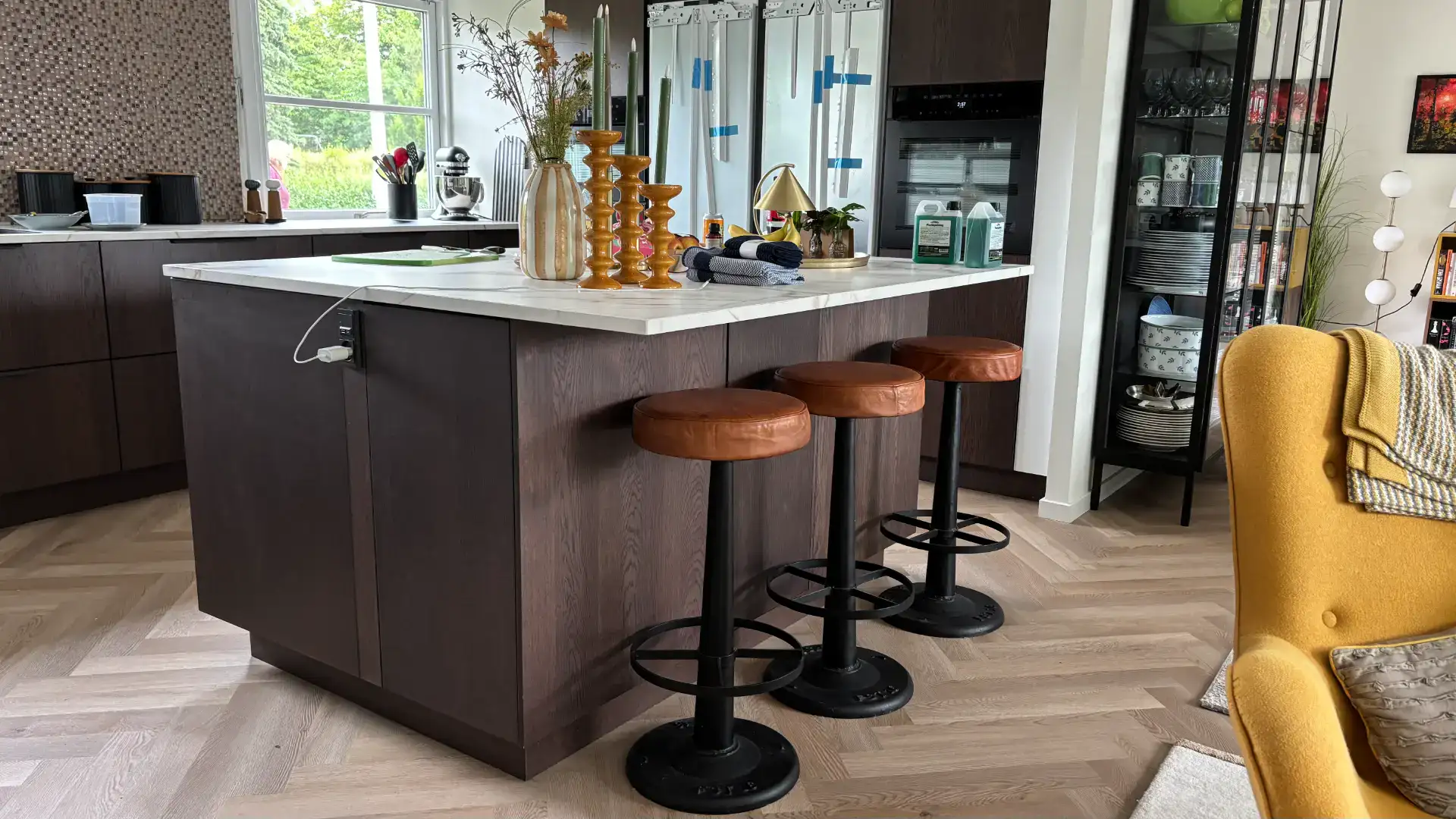 Moderne køkkenø med barstole, åbent køkken med store vinduer og moderne indretning.
