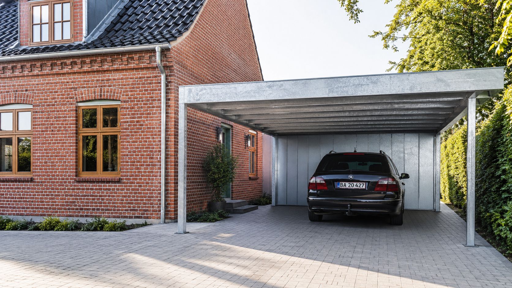 Moderne carport i galvaniseret stål monteret ved siden af et flot rødt murstenshus med en parkeret bil.